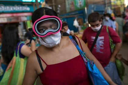 <b>Protección extrema. </b>Una mujer usa una máscara de buzo sobre la mascarilla de tela convencional para intentar protegerse del coronavirus, en Lima, Perú. 23 de marzo.