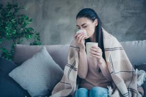 Photo of suffering lady with cup and napkin caught cold drinking medicine from flu covered with blanket wearing pullover and jeans sitting sofa