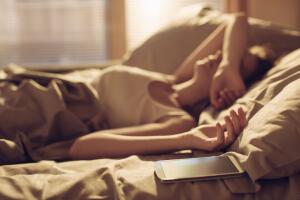 Mujer despertando en su cama junto a su smartphone