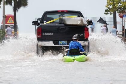 A truck pulls a man on a kayak on a low-lying road after flooding in aftermath of Hurricane Ian, in Key West, Fla. on a street near the Southernmost Point buoy, Wednesday afternoon, Sept. 28, 2022. (AP Photo/Mary Martin)