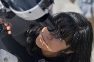 Niña viendo por un telescopio