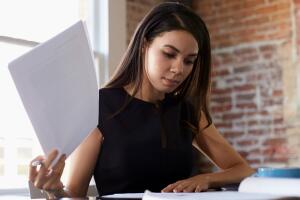 Businesswoman Making Notes On Document In Office