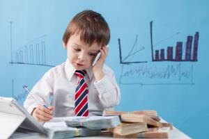 Young boy, talking on the phone, writing notes, money and tablet on the table