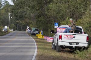 Partidarios de varios candidatos piden el voto a las afueras de un centro electoral en Crawfordville, 