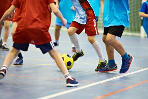 Children playing soccer indoors