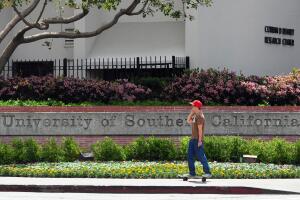 A student rides his skateboard past an e