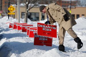 Un simpatizante de Ron DeSantis coloca carteles de su campaña en la nieve en Cedar Rapids.