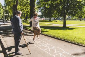 Senior woman playing hopscotch while husband watching her