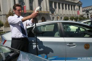El ahora gobernador de California Gavin Newsom, sostiene un cable de alimentación de carga, antes de probar una versión enchufable de un automóvil híbrido y eléctrico Toyota Prius.