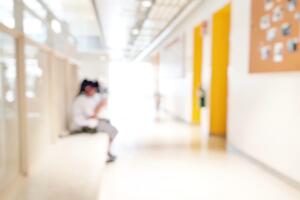 Bullying, discrimination and racism in school concept. Blur sad lonely student sitting alone on walkway looking at smartphone as cyber bully.