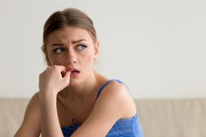 Worried and frightened young woman biting nails