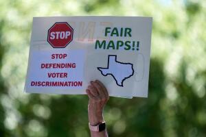 Una mujer sostiene un cartel durante una manifestación de protesta contra las audiencias de redistribución de distritos en el Capitolio de Texas, el jueves 24 de julio de 2025, en Austin, Texas.