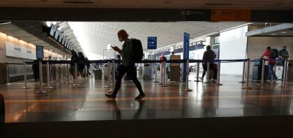 Travelers wear face coverings while passing by the United Airlines ticketing counter in the main terminal of Denver International Airport, Tuesday, Aug. 24, 2021, in Denver. (AP Photo/David Zalubowski)