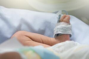 Newborn baby feet and leg with oxygen saturation monitor or pulse oximeter machine, lay in incubator for warming and treated at intensive care unit in a hospital after preterm birth