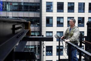 Beekeeper Andrew Cote inspects a large swarm of bees on a building before removing them in the Times Square district of New York