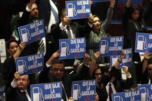 Un grupo de legisladores sostiene carteles de protesta con un mensaje que pide que bajen el precio de la gasolina.