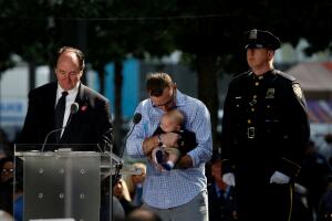 A man holds a young child as names are read of the victims of the September 11, 2001 attacks on the World Trade Center at the National 9/11 Memorial and Museum during ceremonies marking the 16th anniversary of the attacks in New York