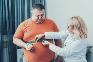 Fat Man with Doctor in White Coat in Gray Room.