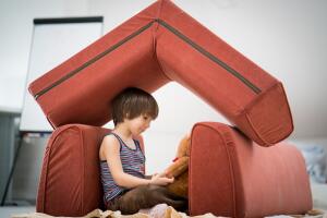 Little boy and Teddy bear with small house made of furniture