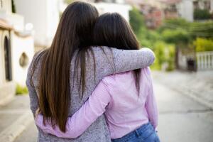 Two identical teenage girlfriends, shot from back