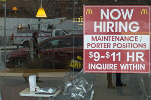 A diner sits next to a help wanted sign at a McDonalds restaurant in the Brooklyn borough of New York