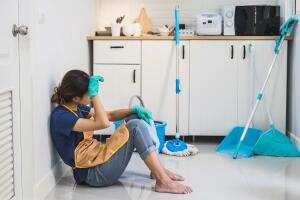Tired young woman sitting on kitchen floor
