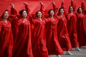 Attendees carry sheets in the colours of North Korea's national flag during a military parade marking the 105th birth anniversary of country's founding father in Pyongyang