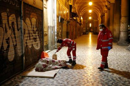 <b>Cuarentena en la calle.</b> Voluntarios de la Cruz Roja llevan alimentos y desinfectante a personas que duermen en las aceras aledañas a la plaza Vittorio, Roma, el 21 de marzo.