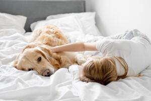 Mujer recostada en la cama con su perro