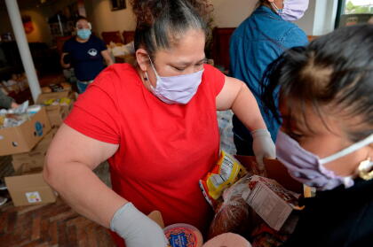 Volunteers and staff for the Chelsea Collaborative Inc. distribute food and packages of donated goods to people in need at the Pan Y Cafe in Chelsea, Massachusetts on April 14, 2020. - Chelsea has the highest infection rate of Covid-19 in Massachusetts and the largest latino and un-documented communities in the state with many families not eligible for state and federal help. (Photo by Joseph Prezioso / AFP) (Photo by JOSEPH PREZIOSO/AFP via Getty Images)