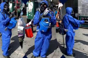 Persona sin identificar y totalmente cubierta reparte máscaras gratis en una esquina de Queens.