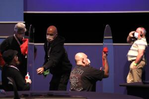 Empleados limpian láminas de plexiglass en el escenario donde la senadora demócrata Kamala Harris debatirá con el vicepresidente republicano Mike Pence, el 6 de octubre del 2020 en la Universidad de Utah, en Salt Lake City.