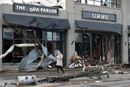 Una mujer camina por una calle cubierta de escombros en la ciudad de Nashville, Tenn. (AP Photo/Mark Humphrey)Un