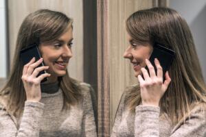 Mujer hablando por teléfono frente al espejo