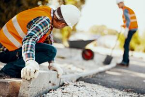 Worker with gloves and in helmet arranging curbs on the street