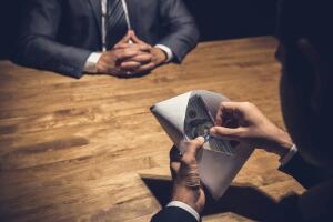 Businessman checking money, US dollars, in the envelope just given by his partner