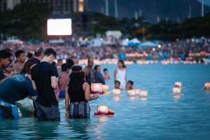 Young couple placing prayer lantern in water Honolulu, Hawaii.