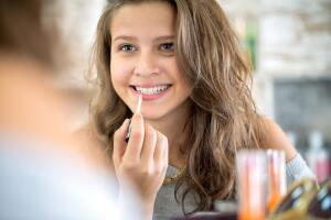 Cute girl applying  lip gloss