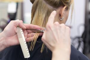 A hairdresser making haircut for a blonde female client
