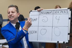 El representante Jared Moskowitz, demócrata por Florida, sostiene una pizarra comparando los juicios políticos y las acusaciones del expresidente Donald Trump y del presidente Joe Biden, el jueves 28 de septiembre. 2023.