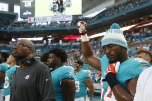 El jugador de Miami Dolphins, Robert Quinn, levanta su puño en protesta mientras sonaba el himno nacional, antes del juego de pretemporada contra los Tampa Bay Buccaneers, este jueves 9 de agosto de 2018.