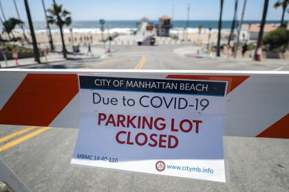 "Estacionamiento cerrado por covid-19", se lee en los anuncios de la ciudad de Manhattan Beach que limita el paso a la zona cerca del mar.