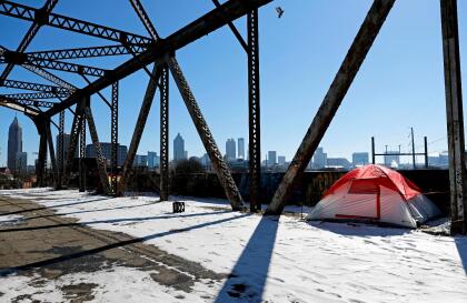 A tent sits in the snow on a bridge frequented by the homeless as the downtown skyline stands in the background in Atlanta, Thursday, Jan. 18, 2018. The deep freeze that killed at least 15 people and shut down much of the South began to relent Thursday as crews worked to clear roads blanketed by a slow-moving storm that left ice and snow in places that usually enjoy mild winters. (AP Photo/David Goldman)