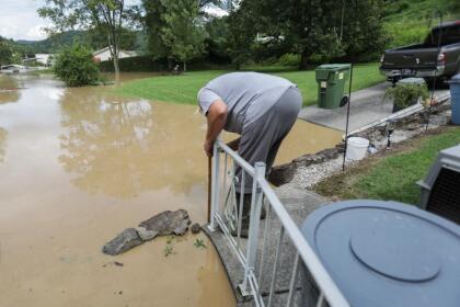 A homeowner measures floodwater from the North Fork of the Kentucky River next to his home in Jackson, Kentucky, on July 28, 2022. - At least three people have died after torrential rains caused massive flooding in eastern Kentucky, leaving a number of people stranded on rooftops and in trees, the governor of the southeastern US state said Thursday. (Photo by LEANDRO LOZADA / AFP) (Photo by LEANDRO LOZADA/AFP via Getty Images)