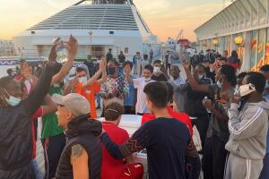 Migrants cheer and dance around Francesco and his piano.jpg