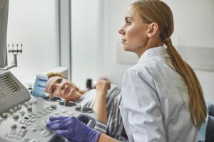 Doctor checking woman pregnancy during sonography procedure