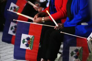 Personas sostienen banderas haitianas y velas durante una vigilia en el Complejo Cultural Pequeño Haití después de que un juez federal impidiera al gobierno de Trump cancelar el estatus migratorio temporal (TPS) para los haitianos. 