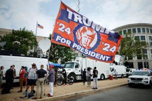 Un hombre ondea una gigantesca bandera con la cara de Trump y la leyenda "Trump para presidente en 2024" en la zona de la avenida Constitución que no ha sido acordonada por la policía y frente a donde se encuentran desplegados los medios de comunicación.