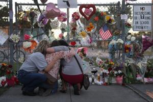 Tres personas se abrazan frente al memorial de la escuela secundaria Marjory Stoneman Douglas en Parkland, Florida, tras el tiroteo que dejó 17 muertos en febrero pasado.