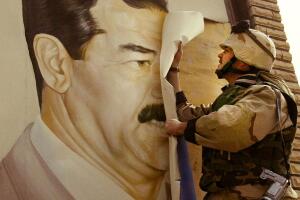 Un marine arranca un afiche de Saddam Hussein en Safwan en marzo de 2003, al inicio de la invasión de Irak que terminó con su salida del poder.